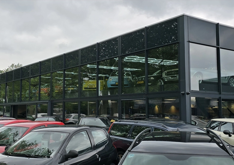Moderne auto showroom in Huizen met grote aluminium kozijnen, aluminium ramen, aluminium gevelelementen en vliesgevel van Aluprof, gerealiseerd met hoogwaardige aluminium geveltechniek, slanke profielen en maximale glasoppervlakken voor optimale zichtbaarheid en lichtinval